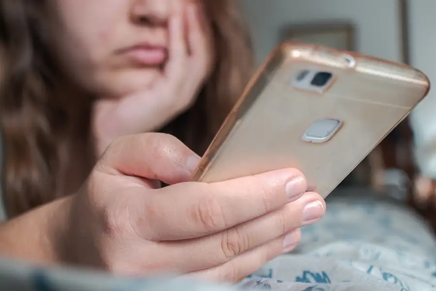 selective focus image of young girl looking bored, scrolling through cell phone - companion image to "Ew, David" slam poem by "Amanda Dzimianski - St. Louis